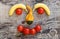 A face made of bananas, tomatoes and a pumpkin on a wooden background