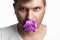 Face of a man with a purple bud of a carnation in the mouth, a flower in the mouth of a man on a white background. Close-up. The