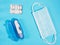 Face masks for protection against viruses, blister of white tablets, clinical thermometer on blue background