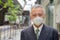 Face of mature Japanese businessman with mask in the city