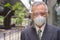 Face of mature Japanese businessman with mask and face shield in the city