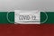 Face Medical Surgical White Mask with COVID-19 inscription lying on Bulgaria National Flag. Coronavirus in Bulgaria