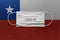 Face Medical Surgical White Mask with COVID-19 inscription lying on Chile National Flag. Coronavirus in Chile