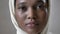 Face ofoung sad african muslim girl in hijab is looks up and watching at camera, religioun concept, grey background