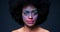 Face paint, art and makeup on black woman with afro in dark studio with unique, creative and fantasy cosmetics on skin