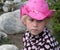 Face pensive little girl in a pink cowboy hat with a seashell