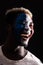 Face portrait of happy afro fan support France national team with painted face isolated on dark background