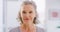 Face portrait of mature woman smiling and standing alone at home. Closeup headshot of happy senior feeling content