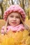 Face portrait of a pensive dreamy smiling girl in a hat and scarf of a rough hand-knitted Christmas winter