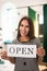 Face-portrait of store owner keeping an open sign in hands