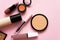 Face powder, brush and various cosmetic decorative makeup products on a color background. Close up. Makeup brush and
