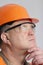 Face profile of thoughtful plump engineer in protective glasses, construction worker in helmet onstudio background