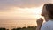 Face profile of young beautiful woman turning to God in nature at sunset, the girl praying folded her hands at the chin, concept o