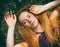 Face of a red-haired woman with freckles on green grass among small beautiful purple flowers