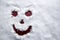 Face scary smiling smiley drawn on white snow, frosty winter day. Close-up.