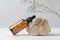 Face serum or essential oil in dark glass dropper bottle near the stone and dried branch of gypsophila flower. Skincare cosmetic.