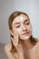 Face skin care. Woman applying facial cleanser on face closeup