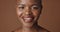 Face, skincare and smile with happy black woman in studio isolated on brown background for wellness. Portrait, beauty