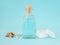 Face tonic or makeup remover in a glass bottle, cotton pads, wooden cotton buds and sea shells on pastel blue background. Hygiene