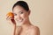 Face. Woman And Fruit Beauty Portrait. Smiling Asian Model With Orange Looking At Camera Against Beige Background.