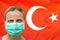 Face of a woman in a mask looking at the camera against the background of the Turkey flag. Influenza from coronavirus, prevention