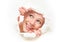 Face of woman peeking through a hole torn in white paper poster