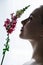 Face of young girl in profile sniffing flower