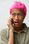 Face of young rebellious Asian woman with pink hair talking on the phone