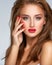 Face of young woman with red nails, lipstick and long brown hair.   Model with fashion makeup