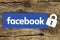Facebook logo with lock placed on old wooden background