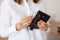 Faceless female wearing white casual style shirt, holding black wallet with money in hands, being ready to go shopping, saving