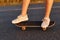 Faceless female in white shoes riding longboard on asphalt road, unknown person skateboarding alone, girls legs on skateboard