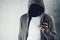 Faceless hooded person using mobile phone, identity theft concept.