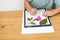 Faceless kid arranging pressed flowers onto a picture frame.