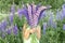 Faceless little kid girl with bouquet of bloom flowers lupines in a field in nature outdoor.