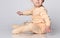 Faceless little toddler toddler child sits on the floor in the studio in a cotton yellow jumpsuit for baby