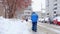 Faceless Male street worker with a shovel removes snow in winter in snowfall, back view. Slow motion