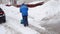 Faceless Male street worker with a shovel removes snow in winter in snowfall, back view. Slow motion