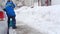 Faceless Male street worker with a shovel removes snow in winter in snowfall, back view. Slow motion