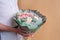 Faceless man holds bouquet of marshmallow sweet flowers in hands. Gift in pastel green wrapper