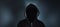 Faceless man in hoodie standing on dark background