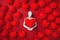 A faceless mannequin holding a large red heart close, surrounded by numerous heart shapes on a deep red background.