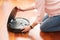 Faceless middle section of young woman opening an automatic vacuum cleaner to clean the floor, machine housework robot