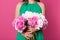 Faceless portait of slim woman holds beautiful bouquet of white and pink peonies in front of his her while standing isolated over