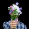 Faceless portrait of man giving bouquet of wild flowers on black background. Greeting card, gift for your loved one, woman`s day,