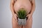 Faceless pregnant woman holding a plant. Metaphor for epilation of the bikini area.