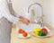 Faceless senior woman in apron preparing vegetables for salad while cooking in modern kitchen at home