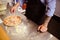 Faceless shot of tattooed chef pouring cheese on pizza near flour in kitchen