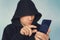 Faceless unrecognizable hooded person using mobile phone, identity theft and technology crime concept, selective focus on body, ha