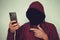 Faceless unrecognizable hooded person using mobile phone, identity theft and technology crime concept, selective focus on body. ha